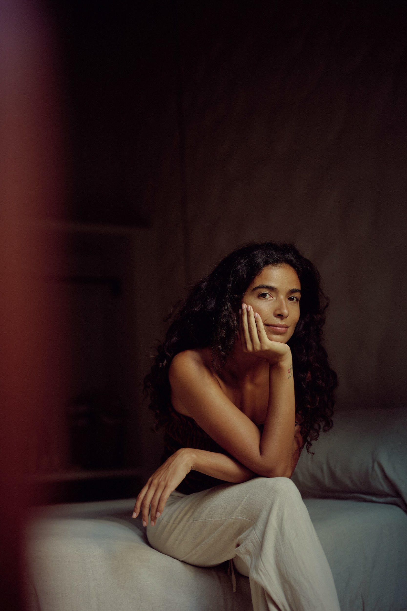 Woman sitting on sofa, hand on chin, looking thoughtfully at camera.