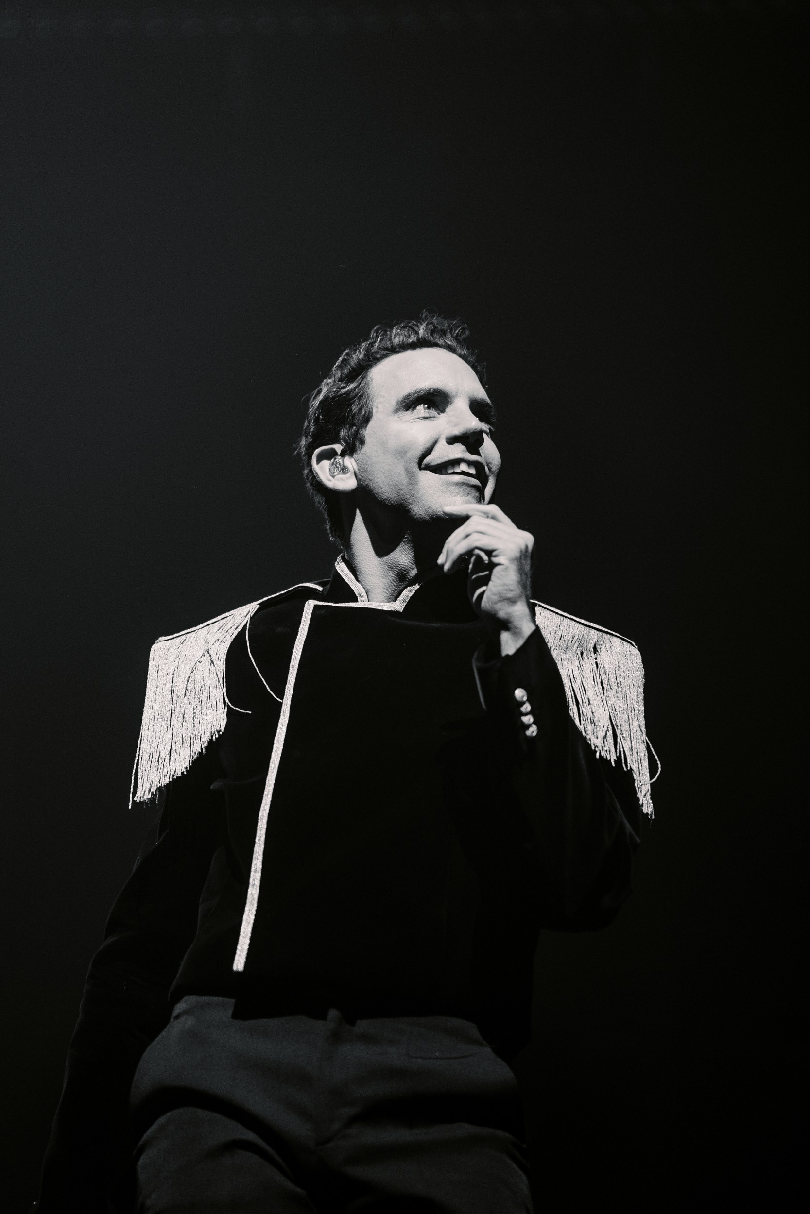 Singer in fringed jacket performing on stage, black and white photo.