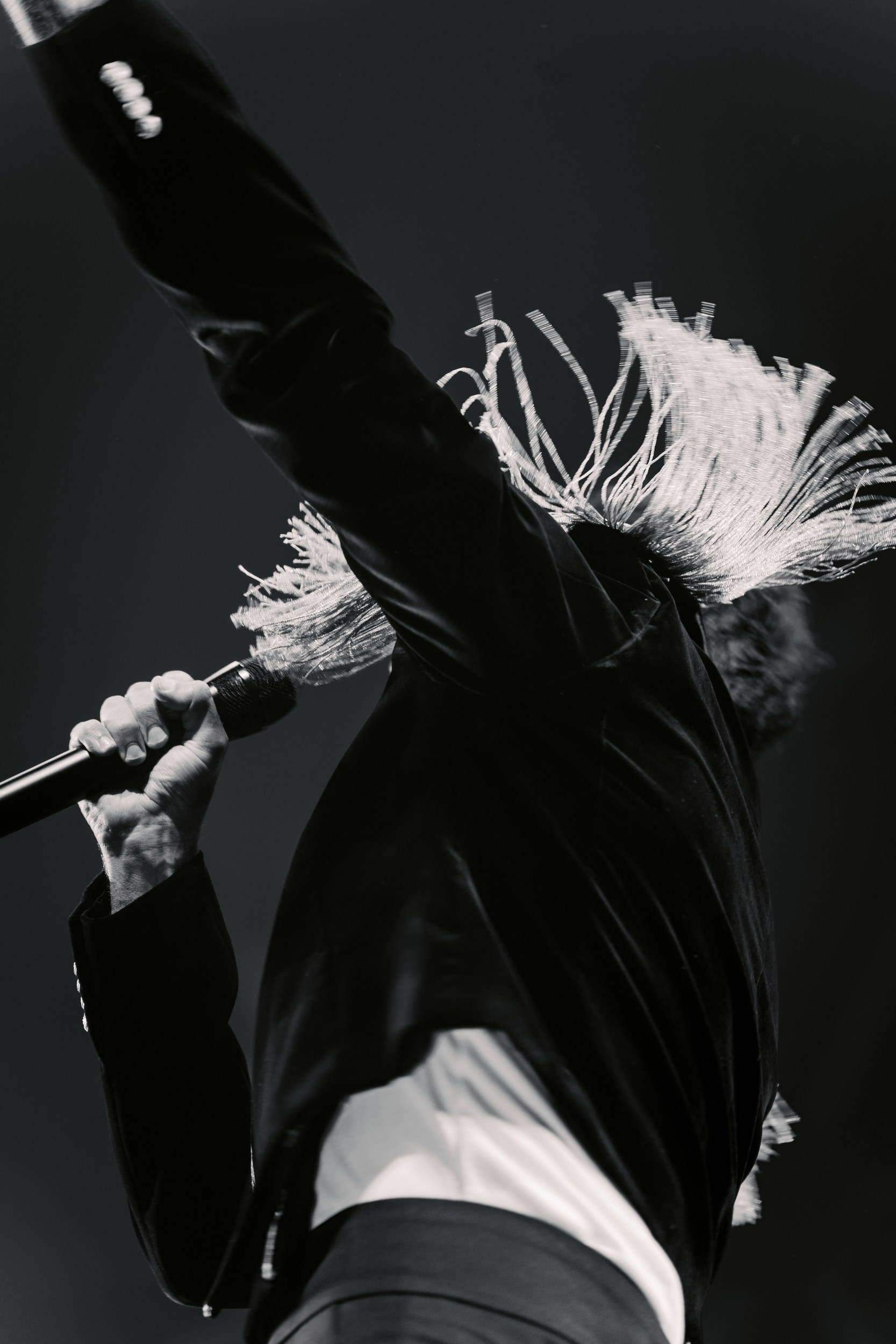 Singer performing energetically on stage with microphone in hand, dramatic angle.