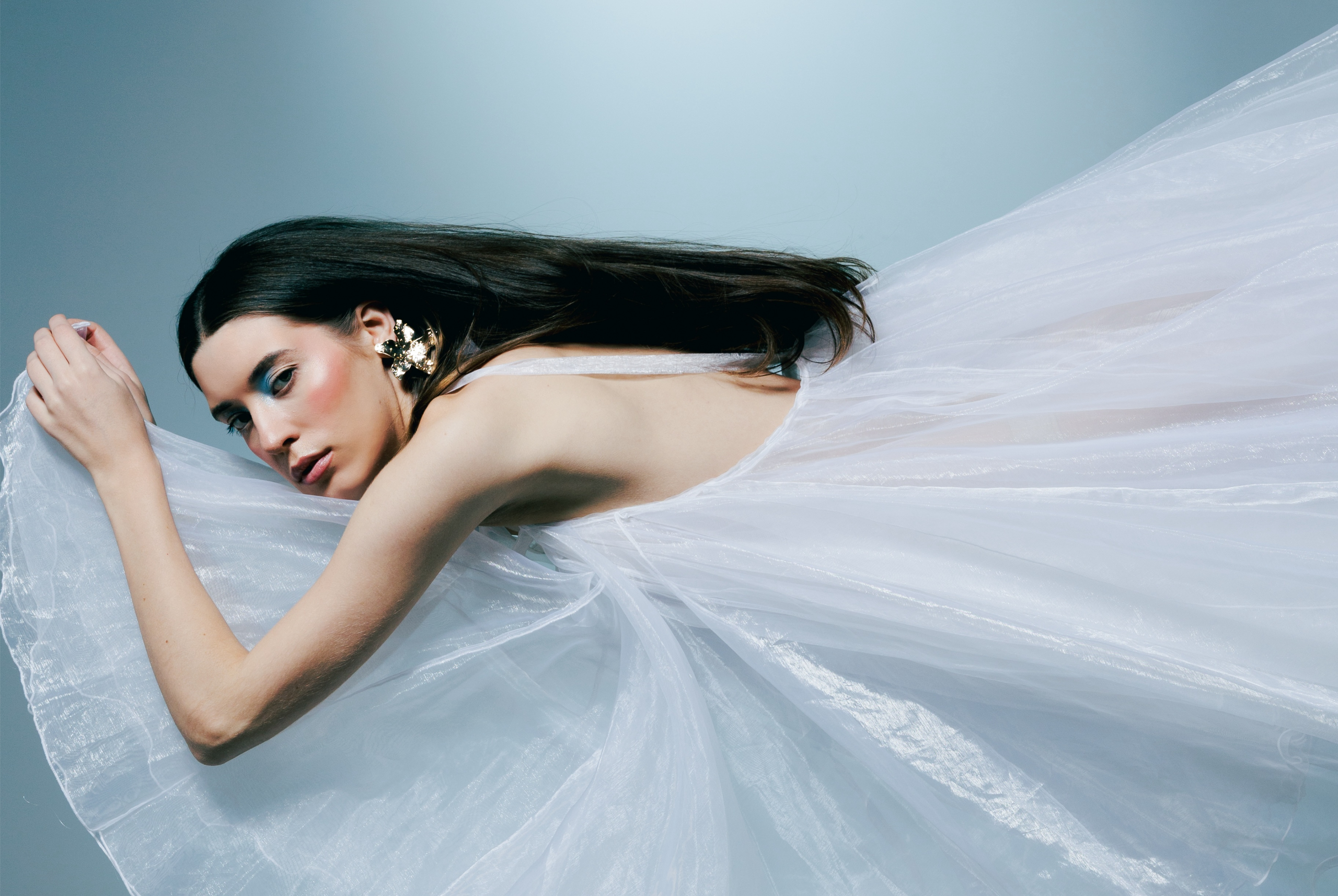 Elegant woman in flowing white dress, artistic fashion pose.