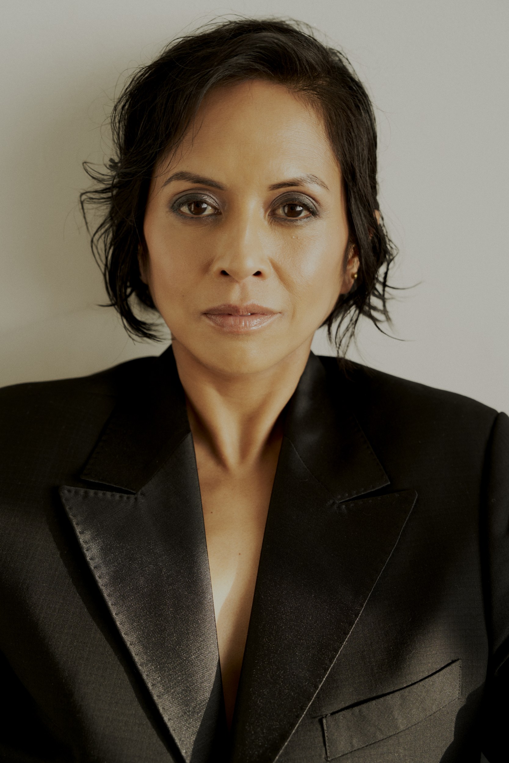 Professional woman in a black suit with short hair and a confident expression.