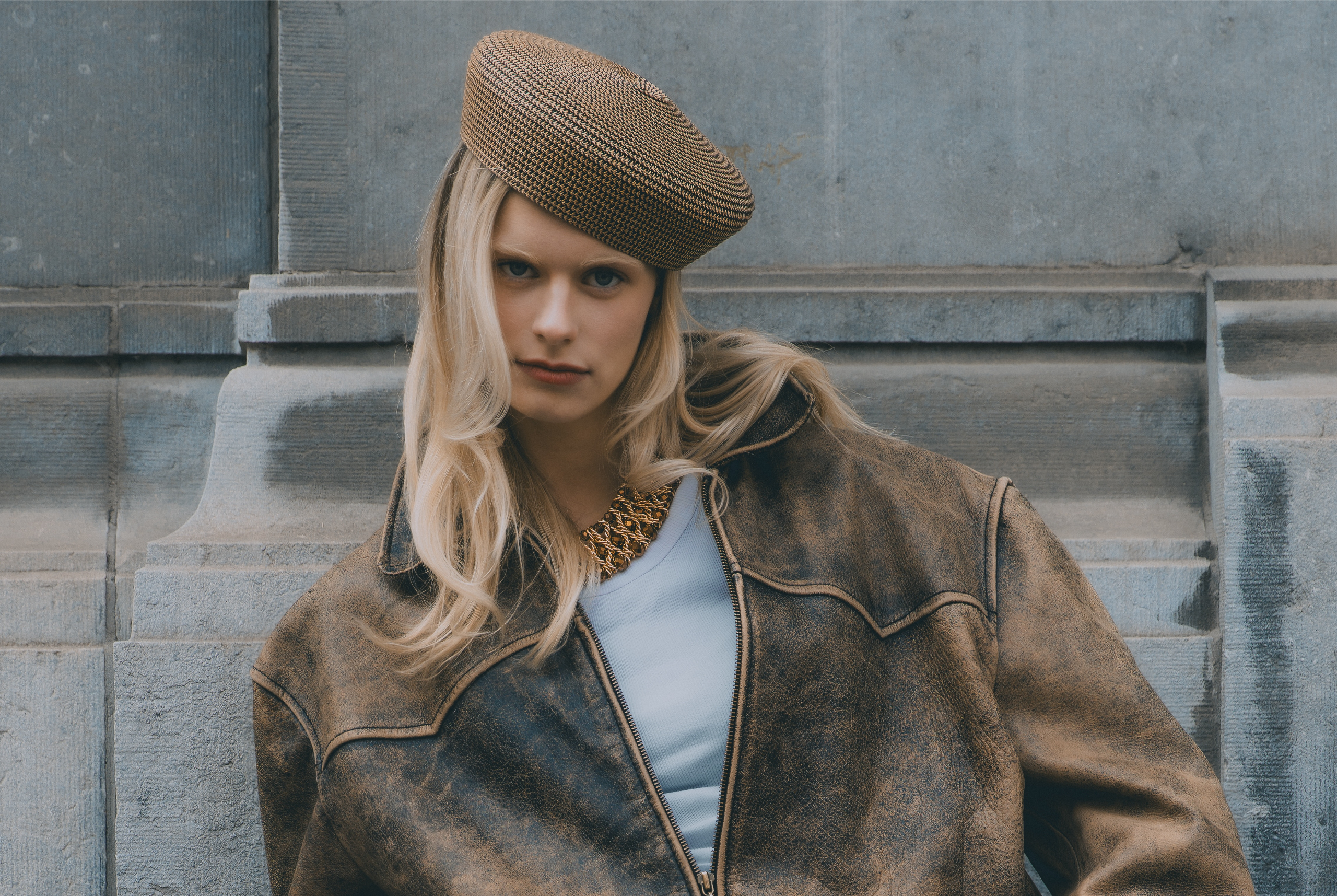 Fashionable woman in a vintage jacket and beret against an urban backdrop.