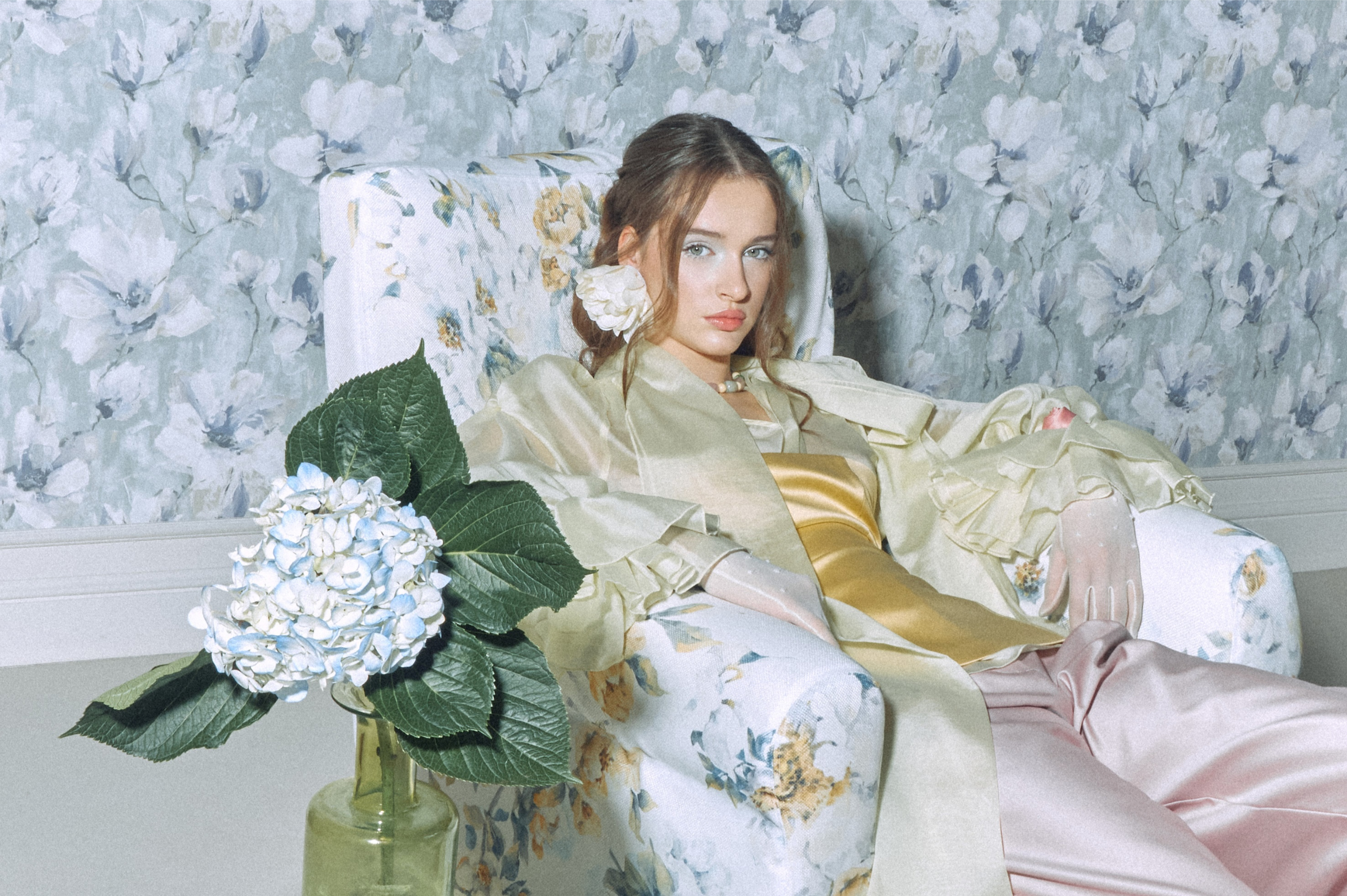Stylish woman in floral chair with hydrangea, elegant and serene.