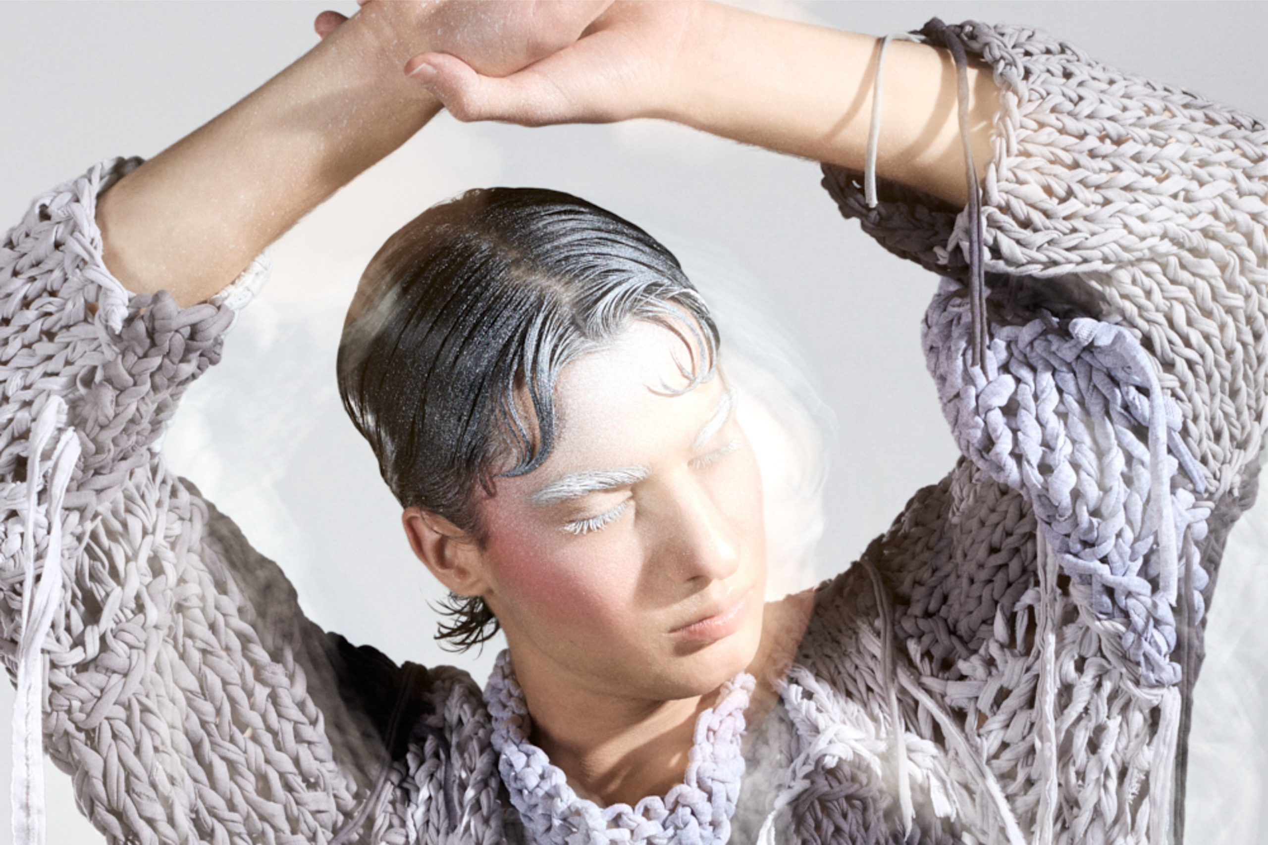 Avant-garde fashion portrait with surreal makeup and textured knitwear.