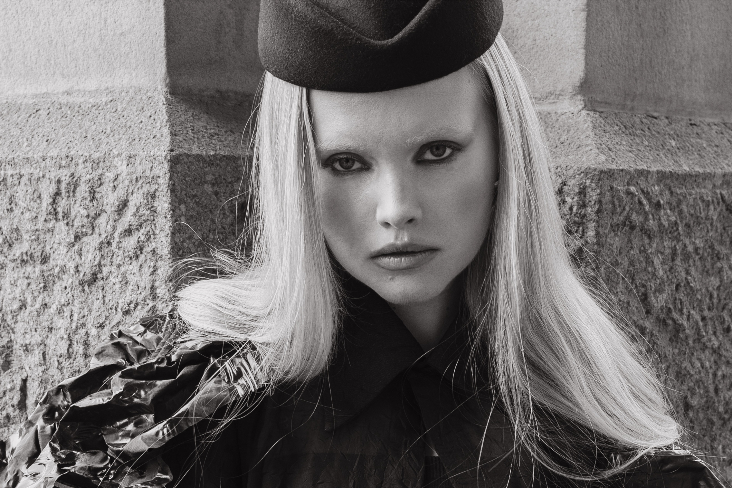 Monochrome portrait of a woman in a stylish hat and textured outfit.