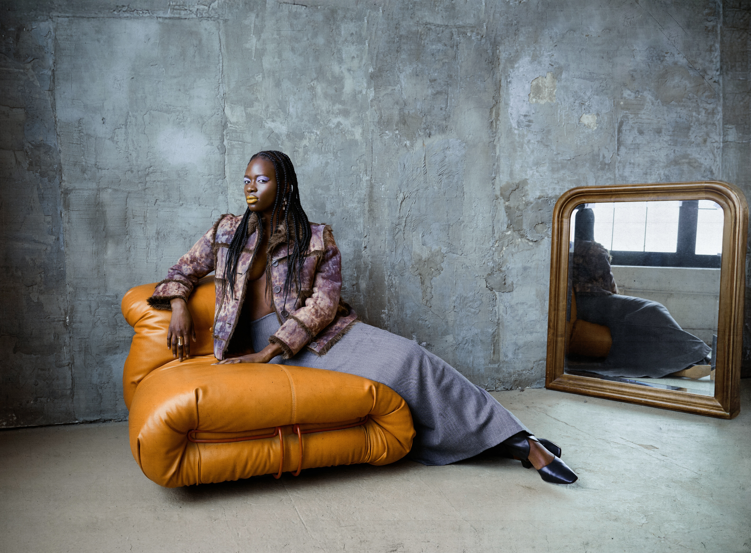 Stylish person reclining on a modern couch with a mirrored backdrop.