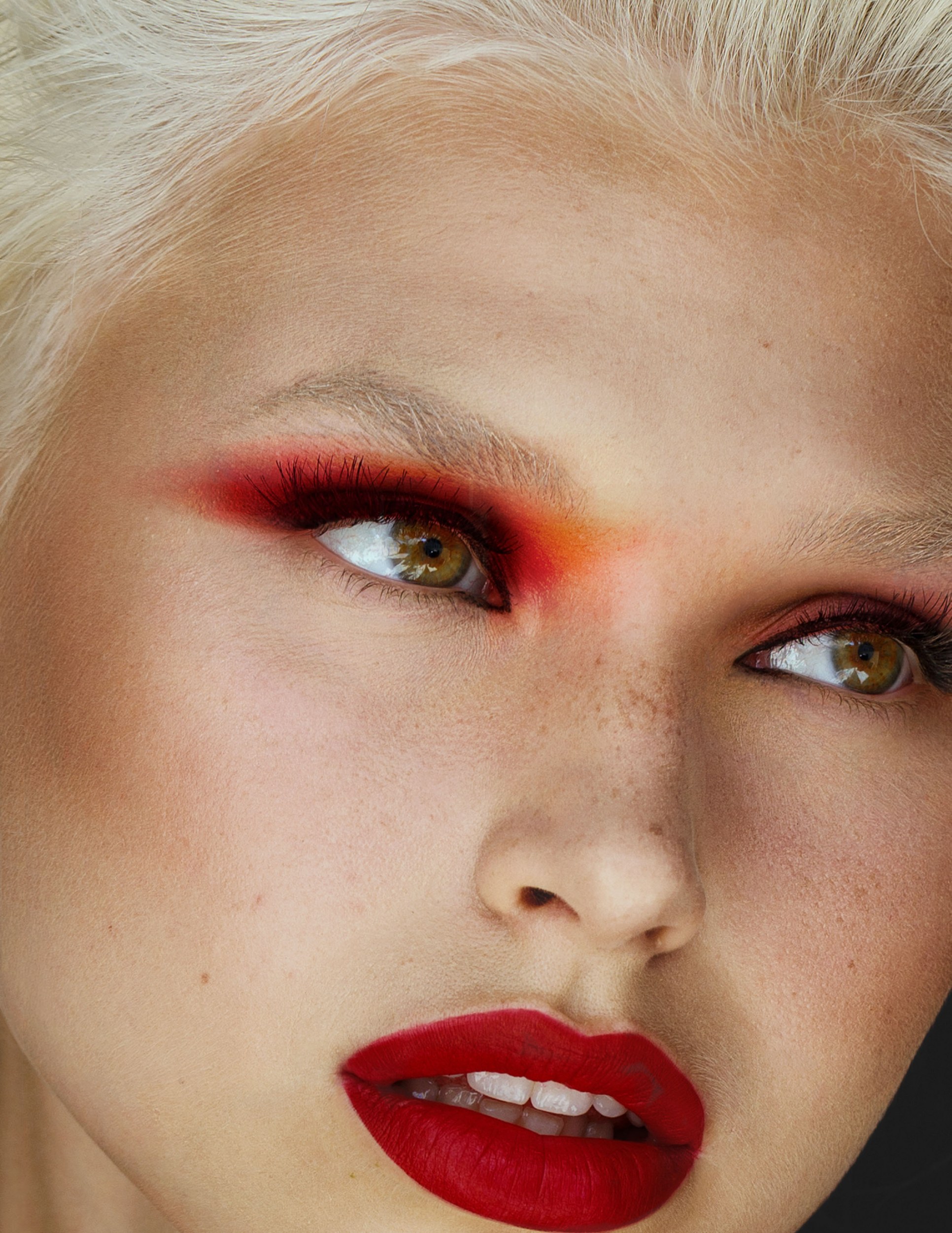 Close-up of a model with bold red eyeshadow and lipstick.