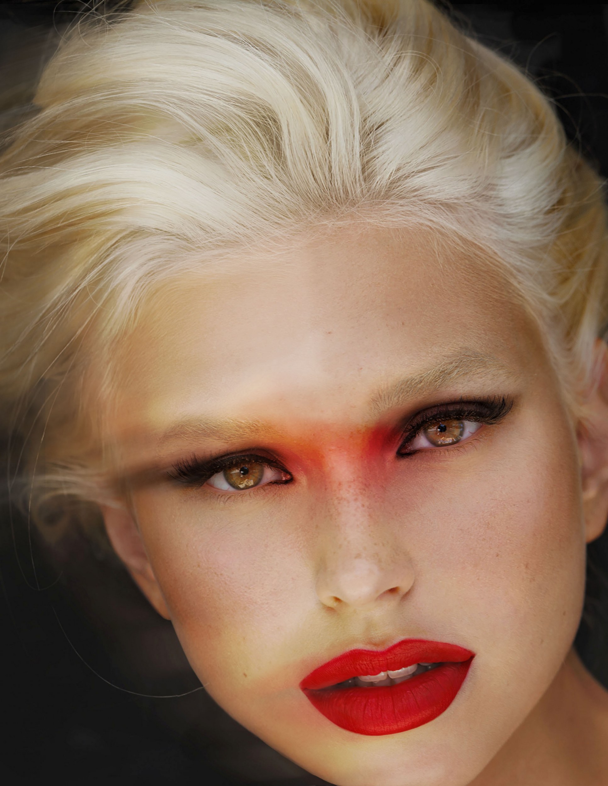 Dramatic makeup look with bold red lips and striking eye shadow on blonde hair.