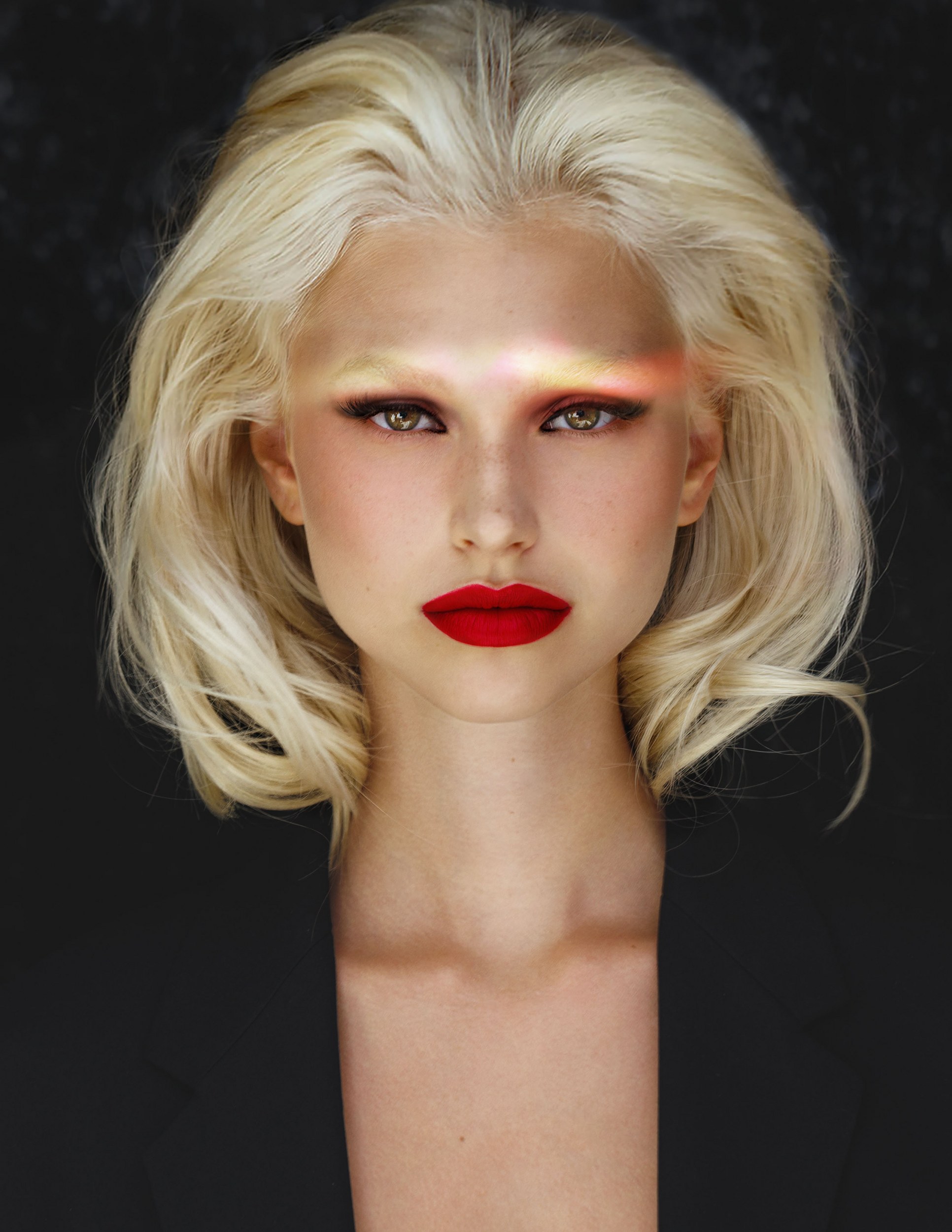 Blonde woman with striking red lipstick and dramatic eye makeup against dark background.