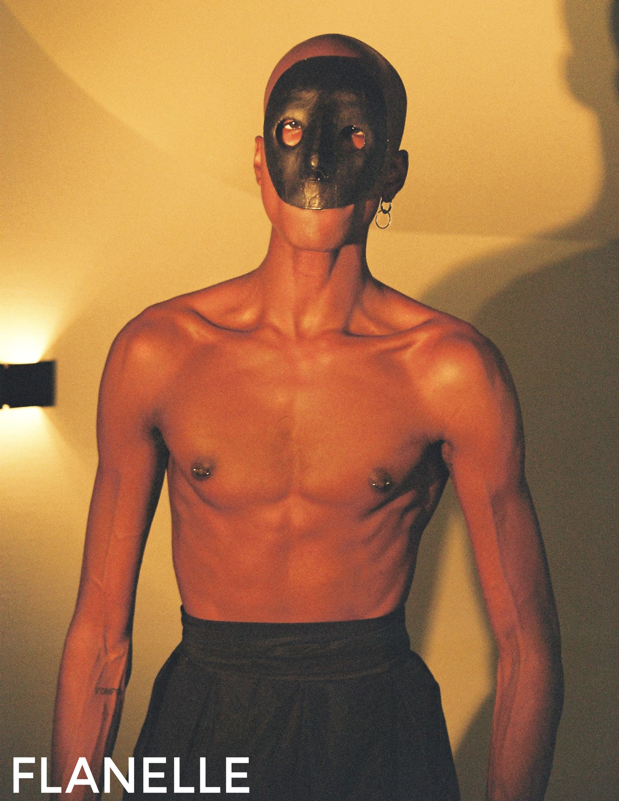 Shirtless person with a black mask, artistic lighting, Flanelle magazine.