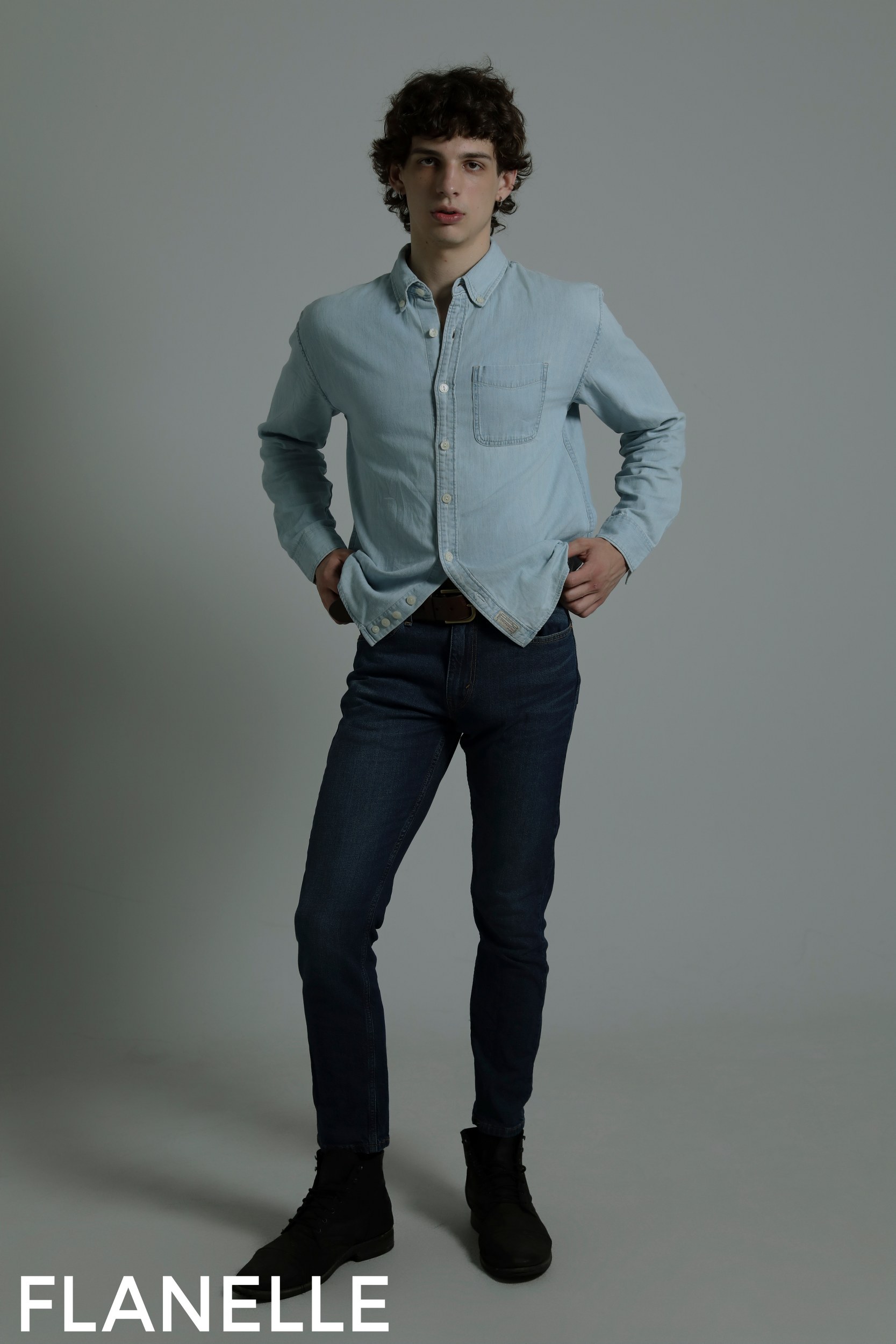 Young man modeling denim fashion in stylish shirt and jeans.