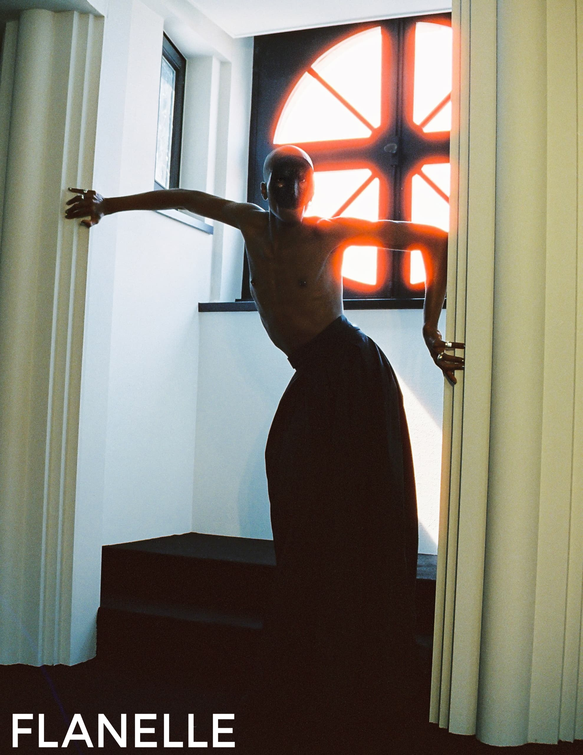 Fashion model posing in dramatic light by a window for Flanelle magazine.