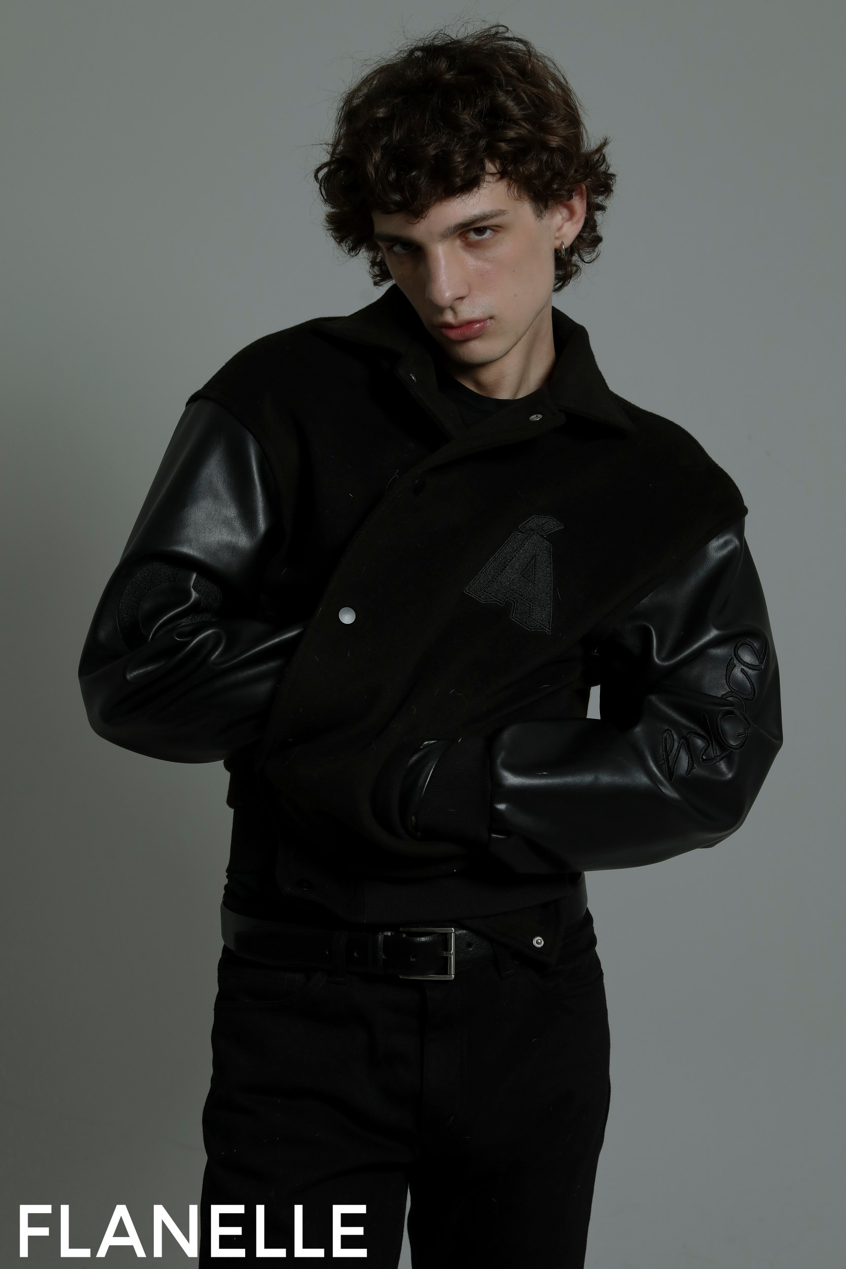 Model posing in stylish black jacket with leather sleeves, fashion shoot.