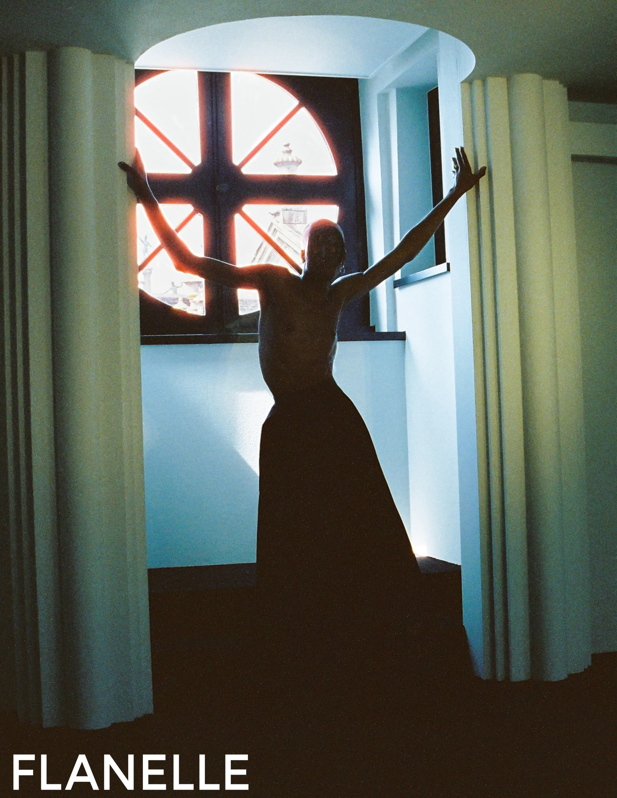Silhouetted figure posing by arched window with dramatic lighting.