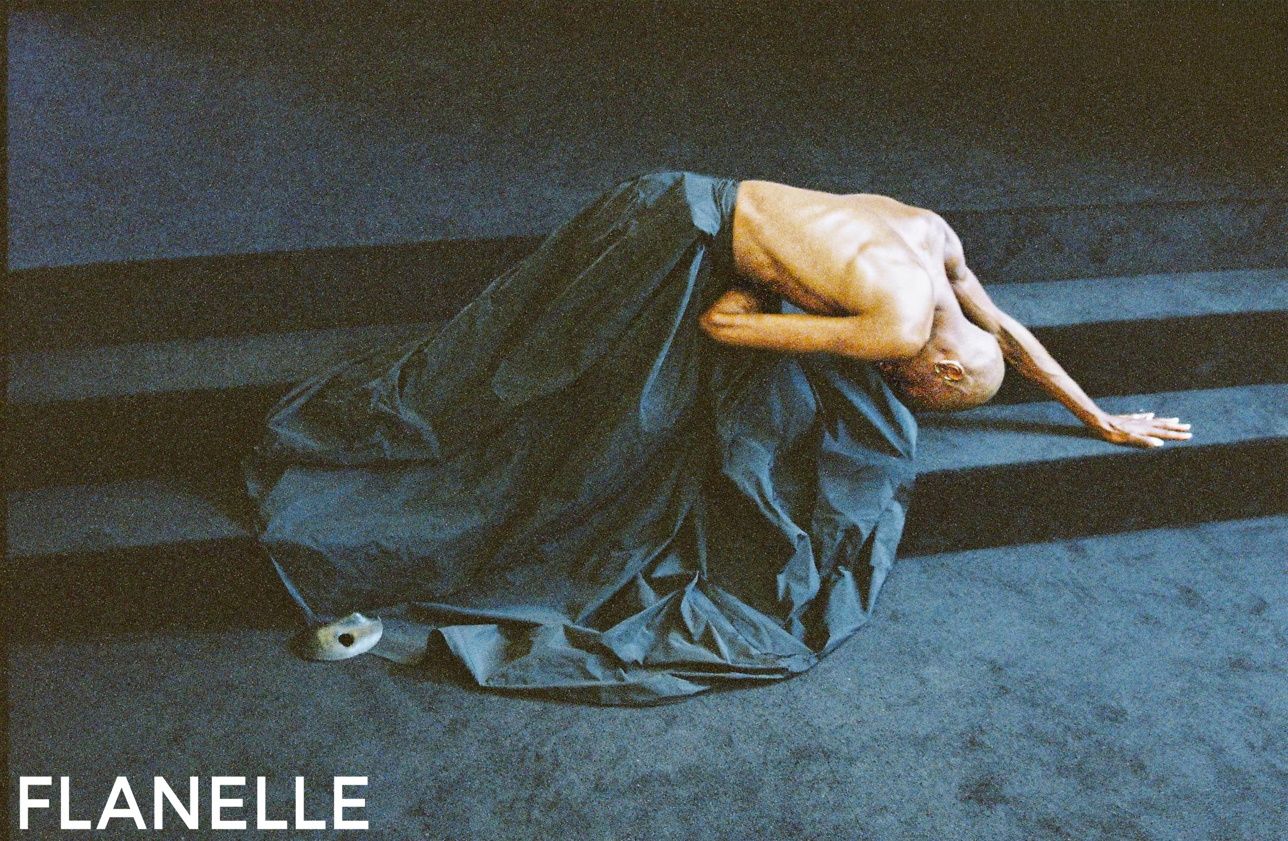 Dancer gracefully bending on stairs in dramatic dark fabric.