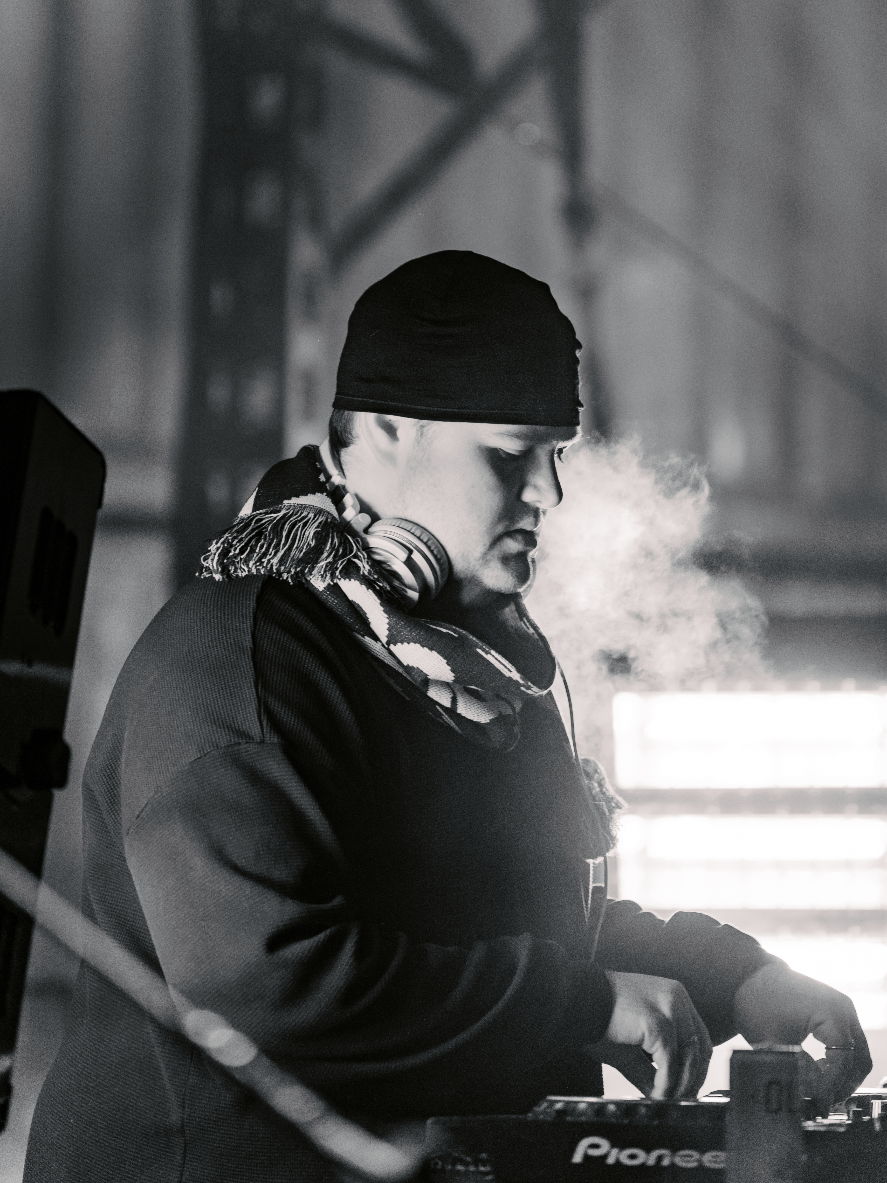 DJ performing live at a winter event, focused and surrounded by misty breath.