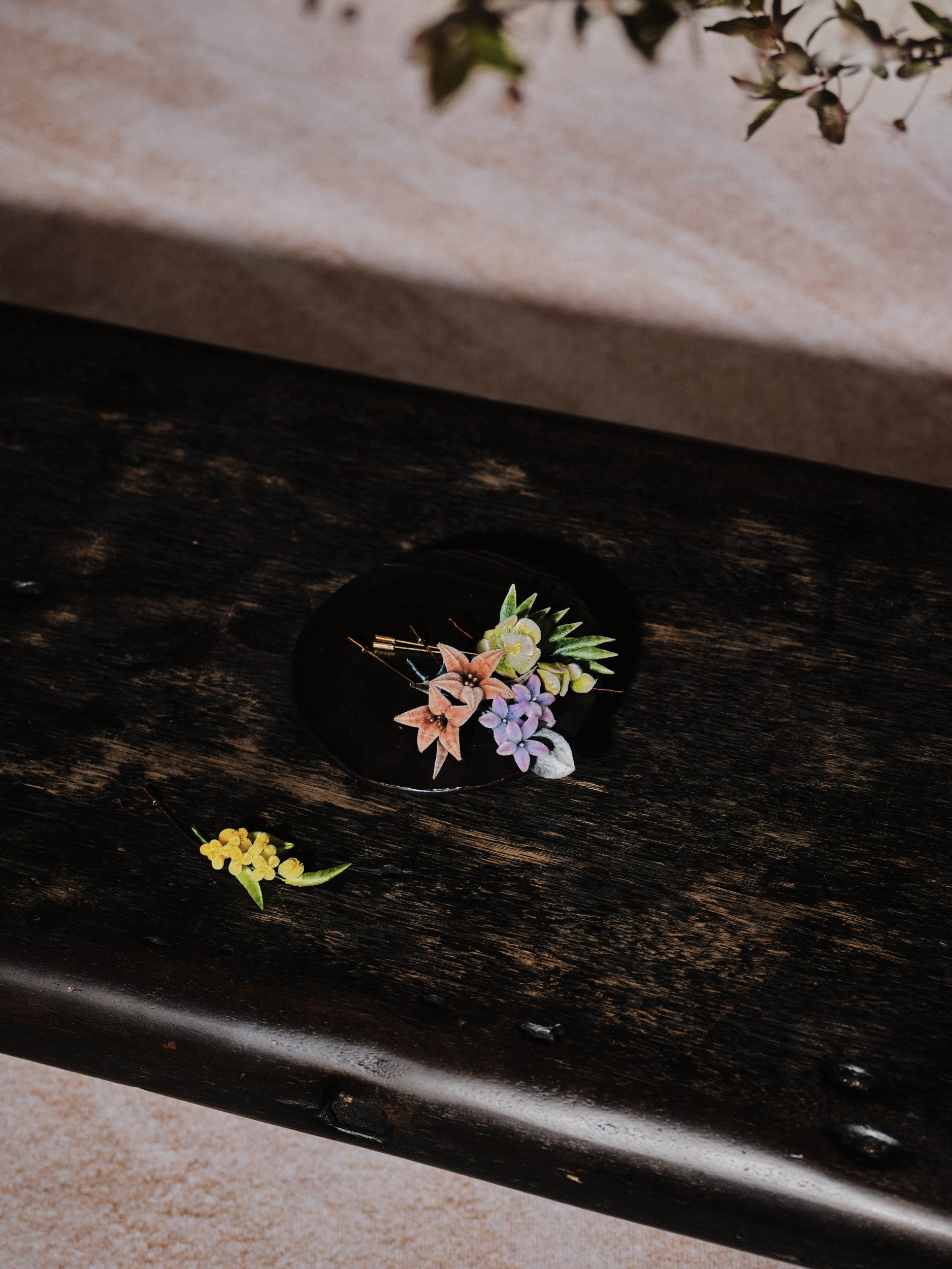 Colorful flowers in a dark vase on a rustic wooden table.