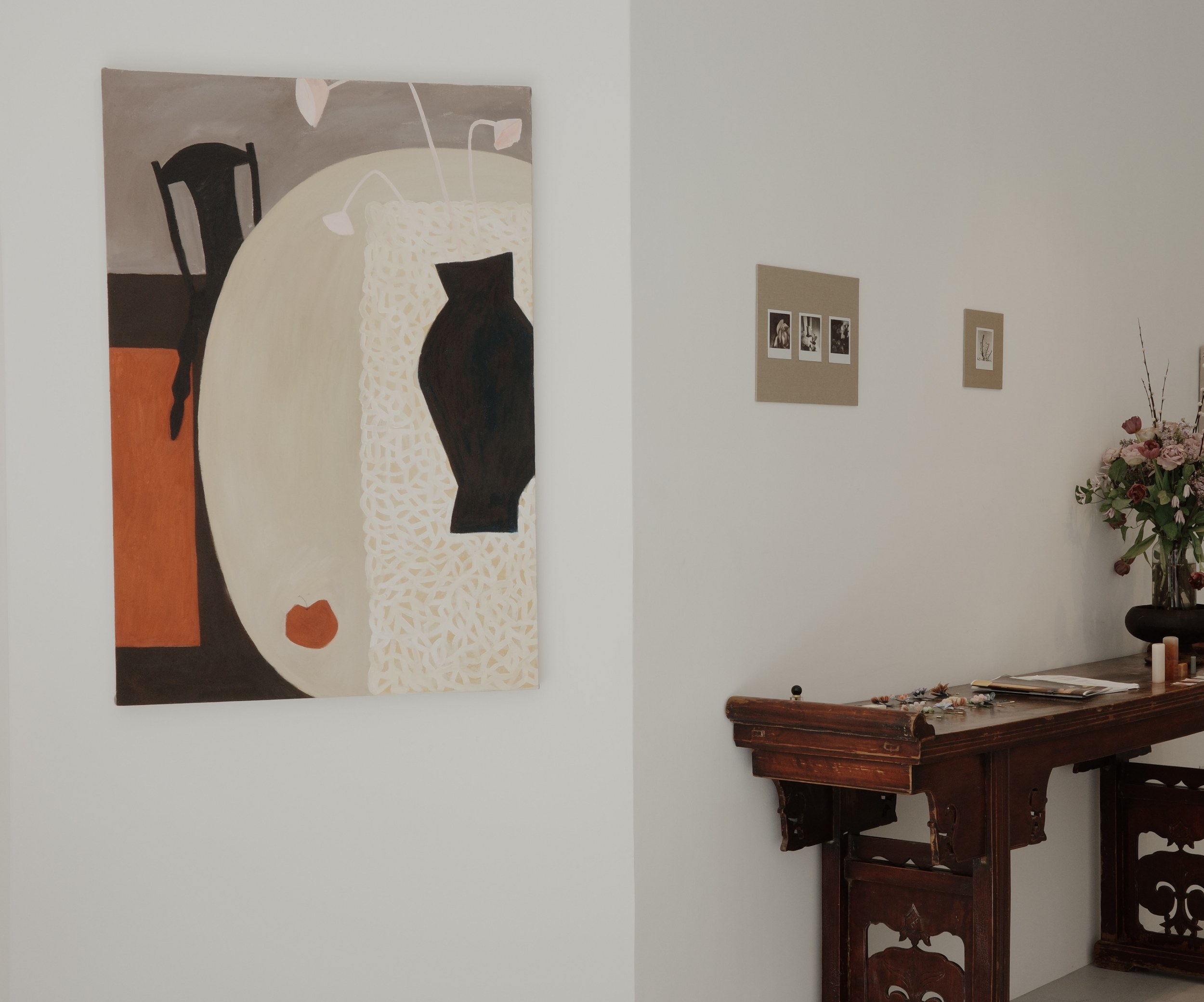 Abstract painting on wall above antique wooden table with flowers