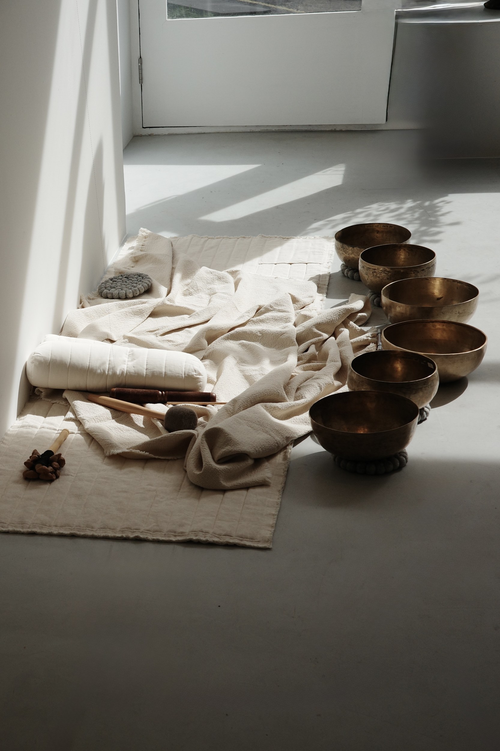 Meditation setup with Tibetan singing bowls and cushions in natural light.