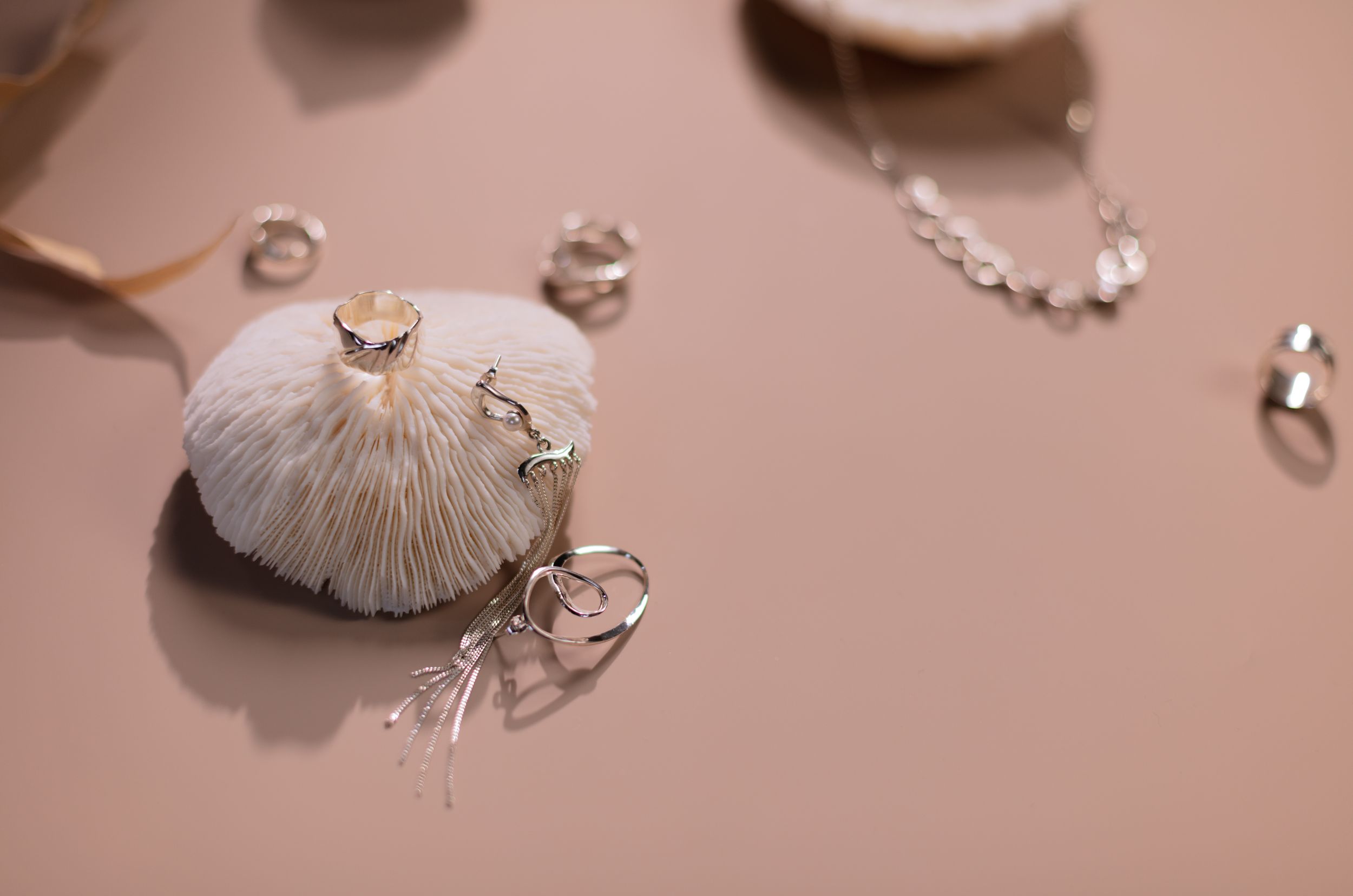 Elegant jewelry set displayed on a seashell with a soft, neutral background.