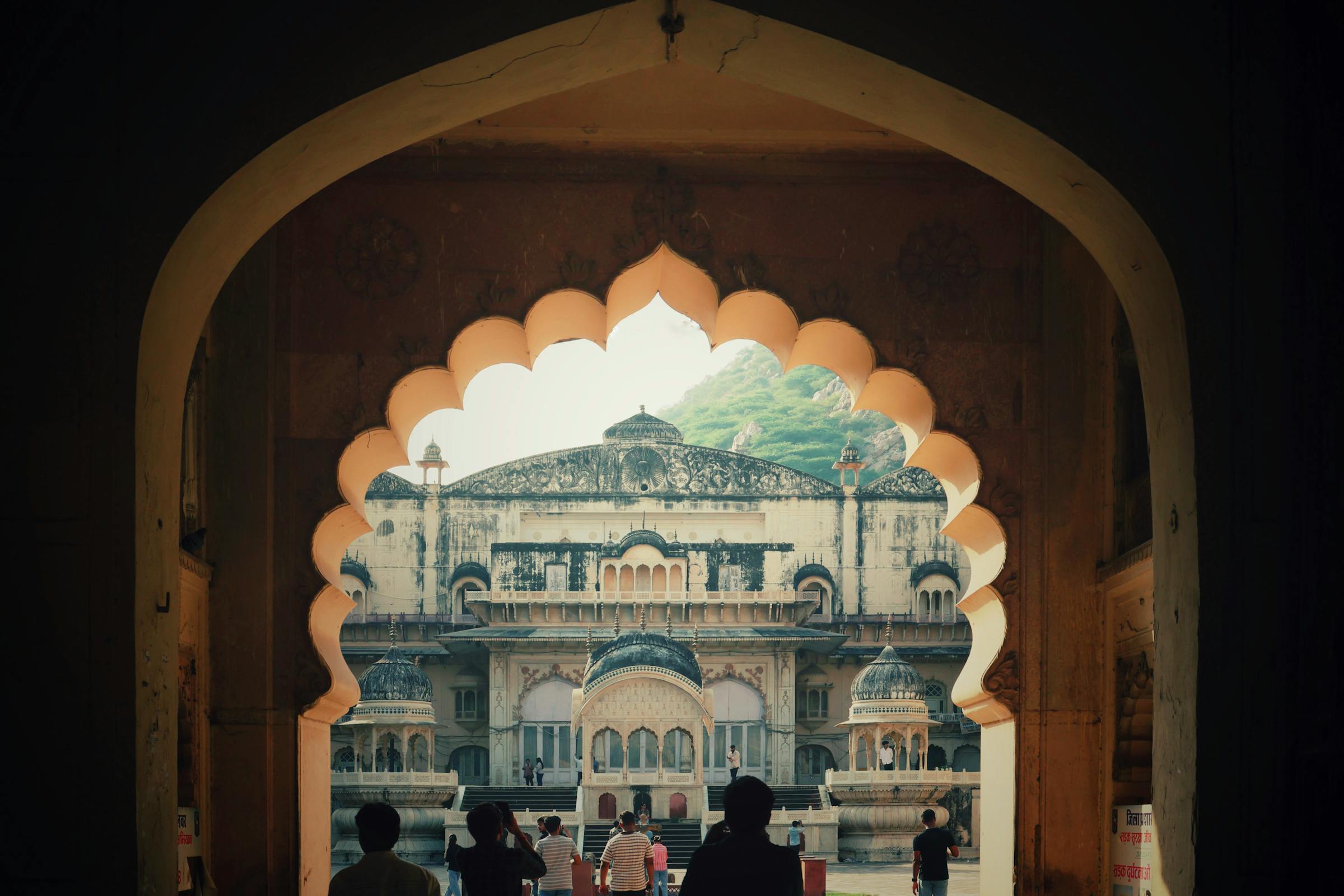 Heritage architecture framed by ornate arch, visitors admire grand historic building.