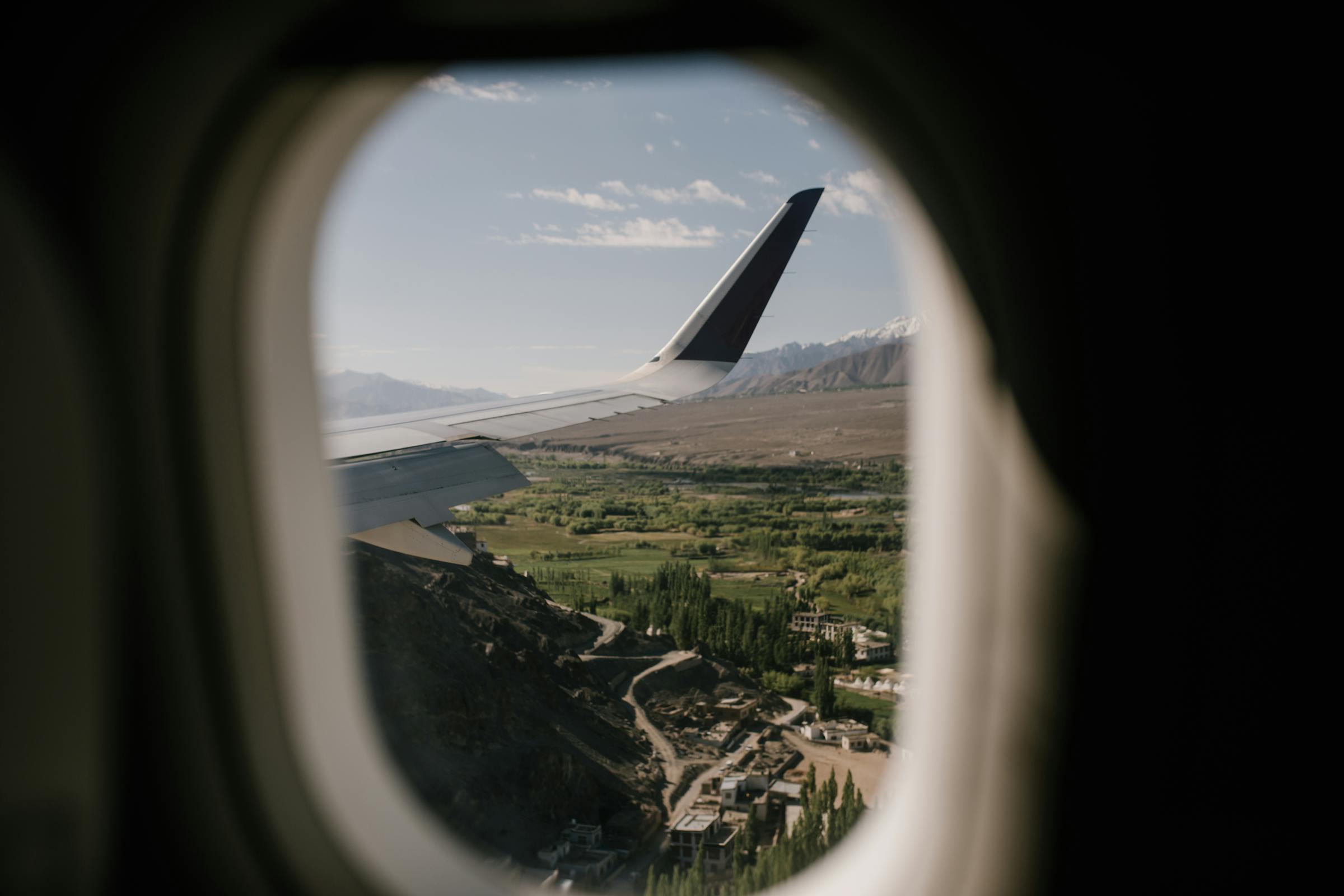 View from airplane window of scenic landscape and wing in flight.