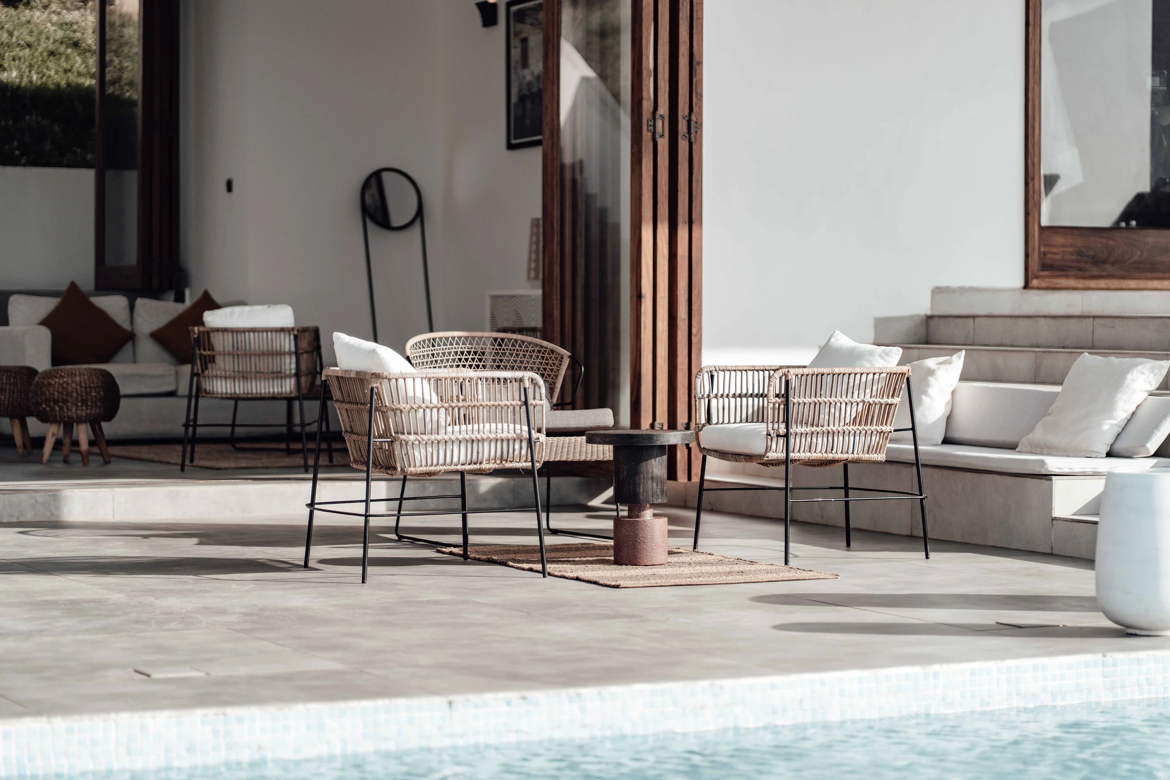 Stylish patio with wicker chairs and a poolside view basking in the sun.