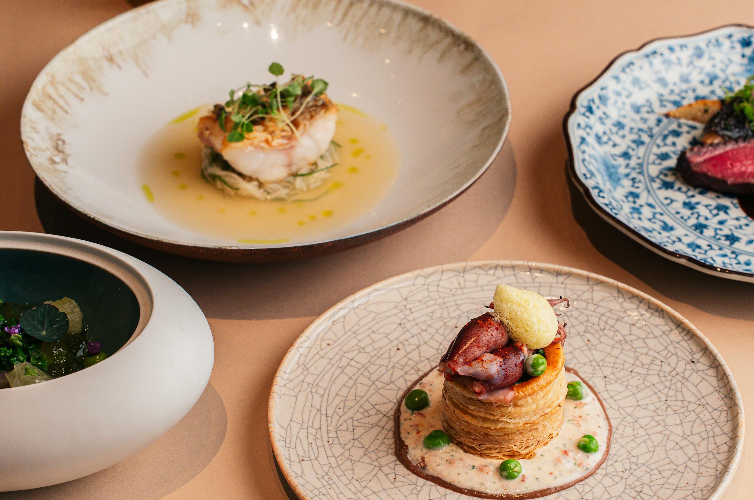 Gourmet dishes beautifully plated on elegant ceramic plates at a fine dining restaurant.