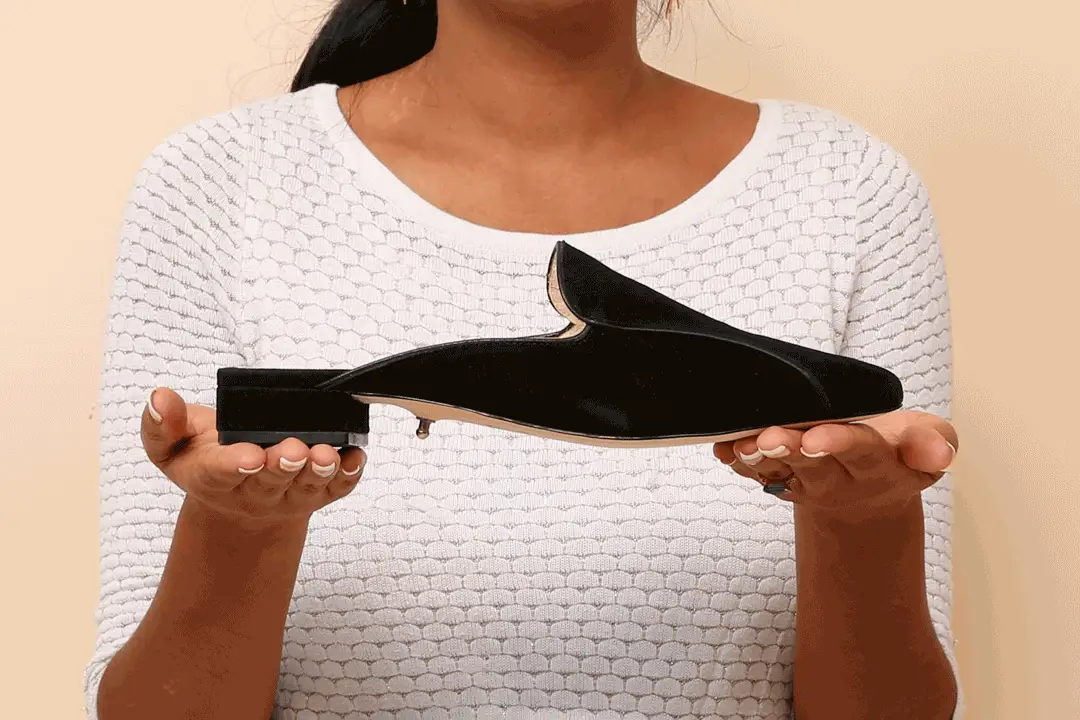 Woman holding oversized velvet shoe in both hands, highlighting unique style.